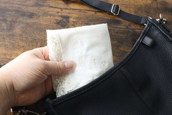 黒いバッグのポケットにハンカチを収納する手