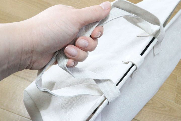 片手でランドリーバッグのハンドルを持ち運ぶ様子