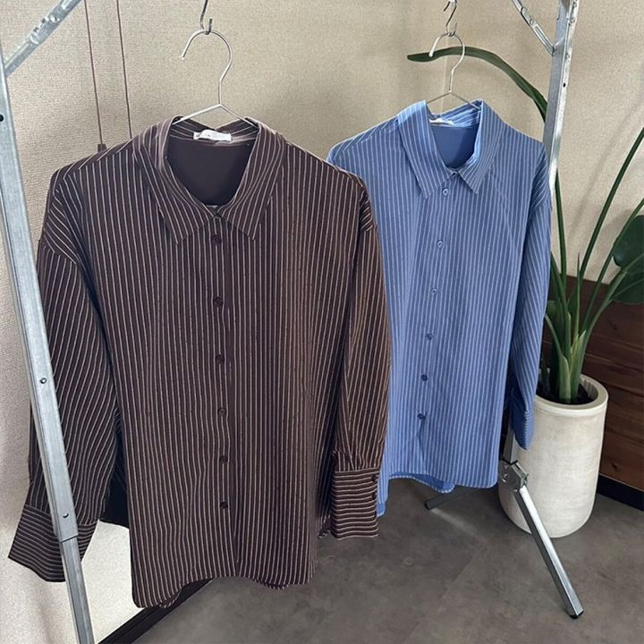 ブラウンとブルーのストライプシャツがハンガーにかかっている