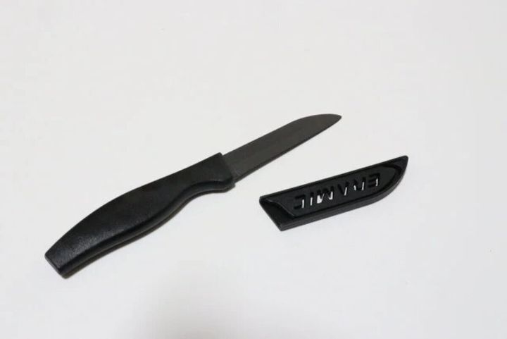 黒いセラミックナイフと、その専用の黒いサヤが白い背景に置かれている