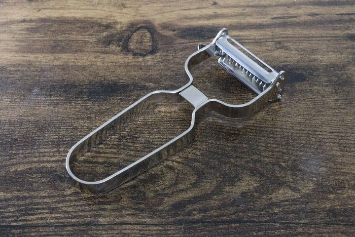 木製のテーブルの上に置かれたオールステンレス製の2WAYピーラー