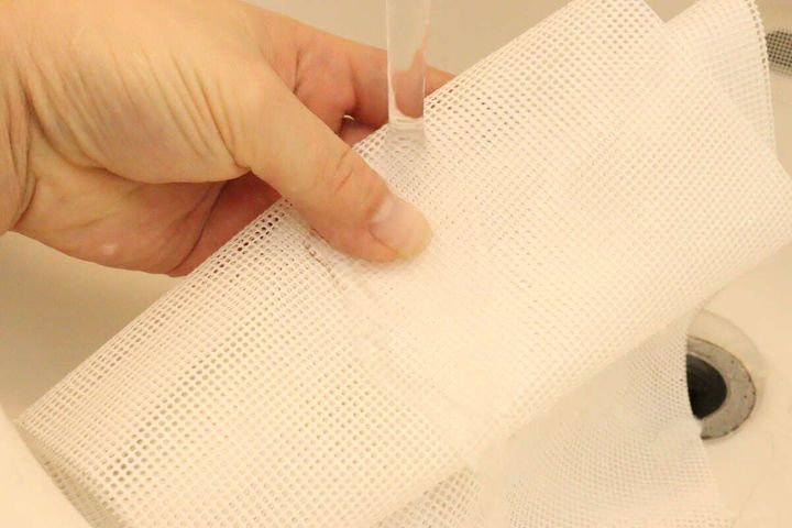 白いシリコーンボディタオルを蛇口から出る水で濡らしている手元