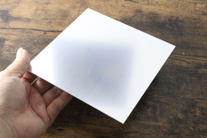白い肌の指がステッカーミラー本体の角を掴んでいる様子