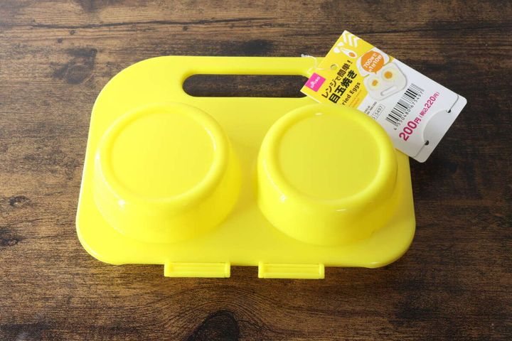 黄色いレンジ用目玉焼き調理器が蓋を閉じた状態で置かれている俯瞰写真。商品タグ付き。