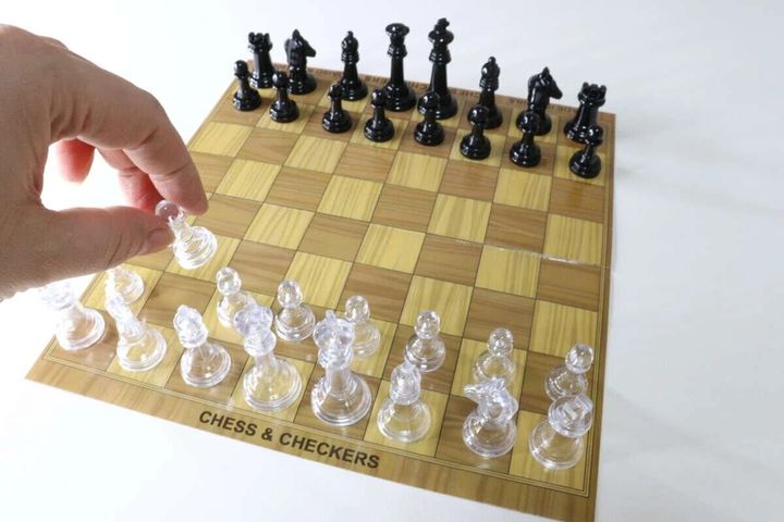 チェス盤に駒が並び、手が透明なポーンを動かそうとしている