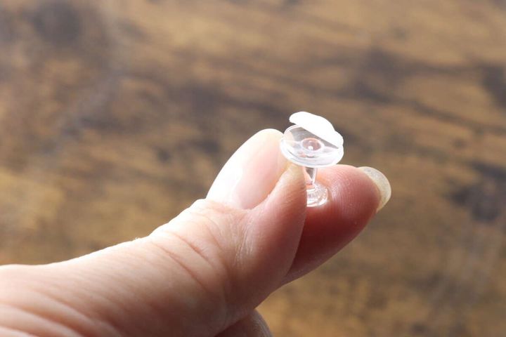 指でフックの粘着テープの剥離紙を剥がす様子
