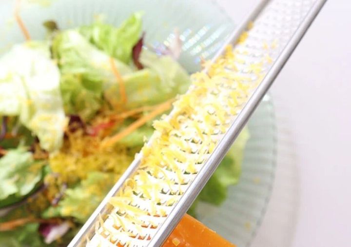 チーズグレーターでサラダの上にチーズを削りかけている様子