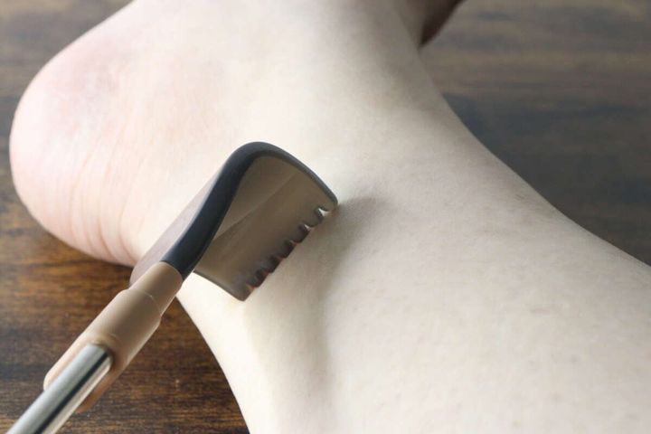孫の手のヘッド部分で足首を掻いている様子