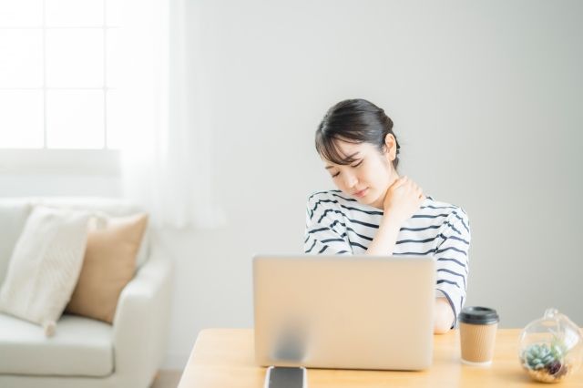 在宅イメージ PCを開いて肩に手を当てる女性 肩こりイメージ