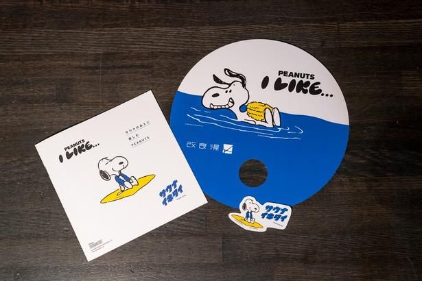  来場特典の非売品うちわと、冊子「サウナのあとに楽しむPEANUTS」、コラボステッカー
