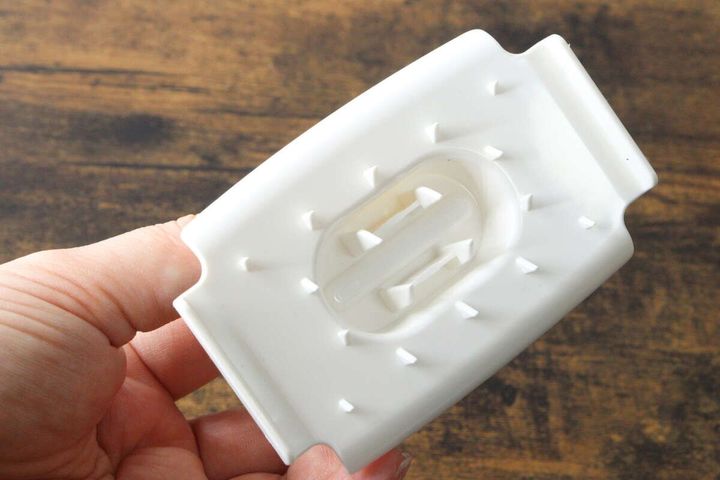 手に持たれたスライサーのホルダー。食材を固定するトゲトゲが見える