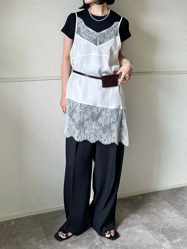 黒Tシャツに白レースキャミソールと黒パンツを重ね着した女性