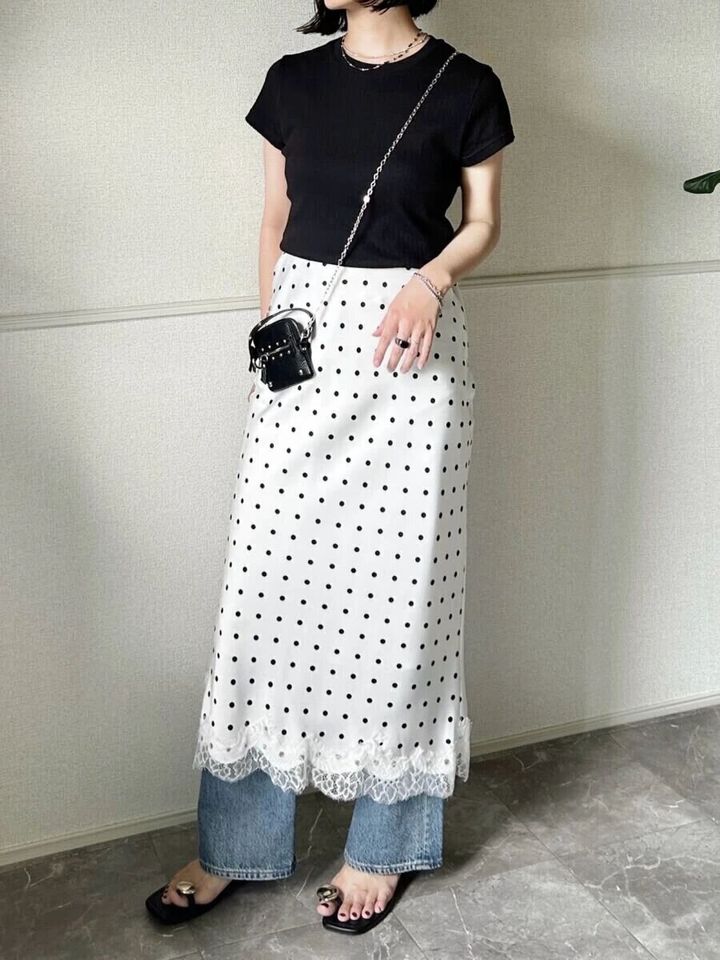 黒Tシャツにドット柄レーススカートとデニムを重ね着した女性