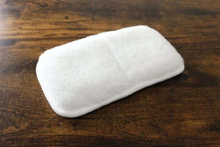 木目のテーブルに置かれた白い「はさめるスポンジ」。