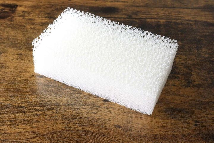 木目のテーブルに置かれた白い速乾キッチンスポンジ。