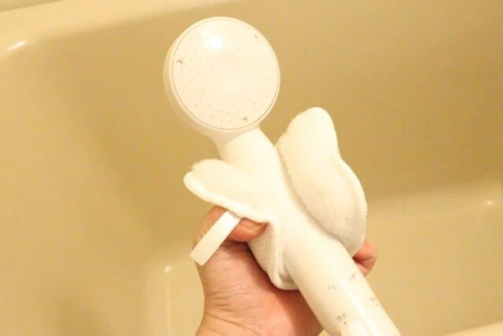 白い「はさめるスポンジ」でシャワーヘッドを挟んで掃除している手元。
