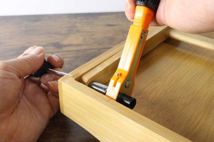 ラチェットツールセットを使って木製の箱の狭い箇所のネジを締めている作業風景