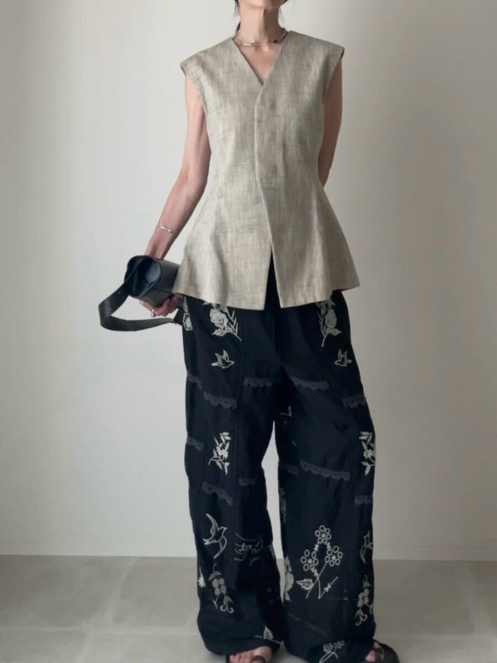 ベージュのペプラムジレと刺繍柄パンツを合わせた女性