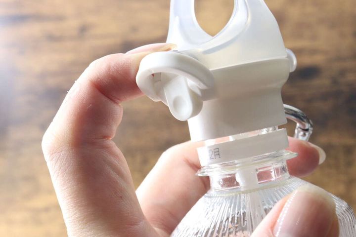 指でペットボトルキャップのロックパーツを操作する様子