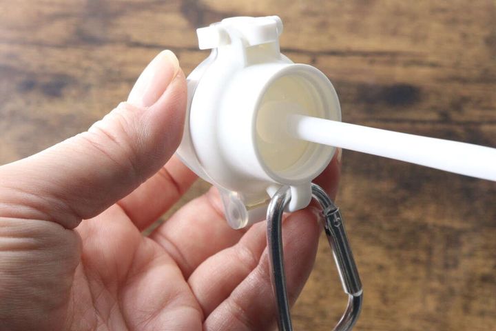 指でペットボトルキャップにストローを差し込む様子