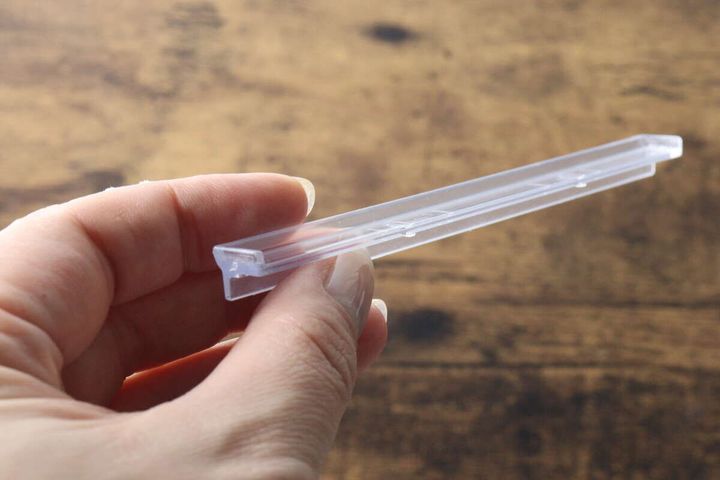 女性の指でつまんだ透明なハンガーストッパーの側面