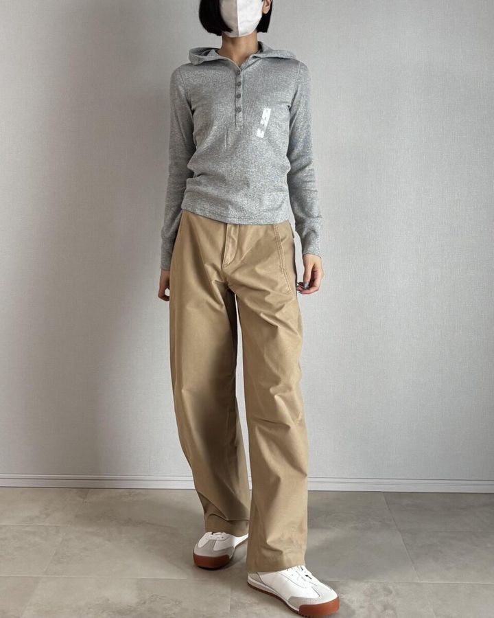 グレーのフーデッドリブTとベージュバレルレッグパンツの女性