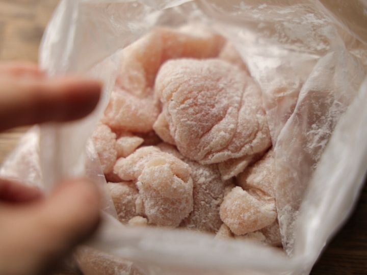 ビニール袋の中で片栗粉がまぶされた鶏むね肉のそぎ切りを指で示している様子
