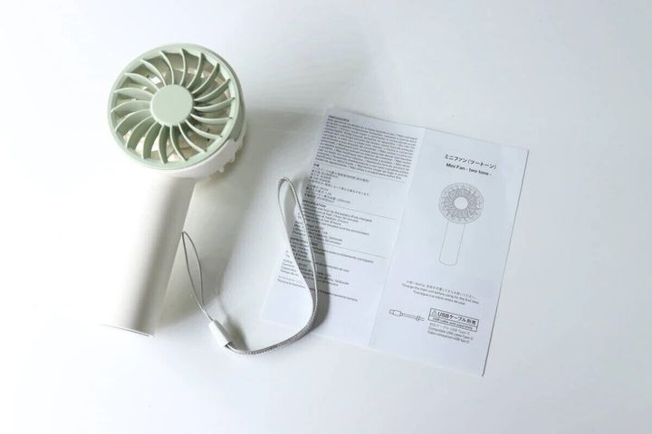 ミントグリーンと白のミニファン本体と、取扱説明書、ストラップが置かれている