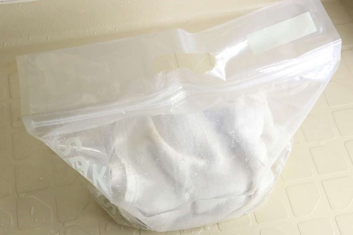 透明なジッパー付き袋の中に白いタオルと水が入っており、袋が閉じられている
