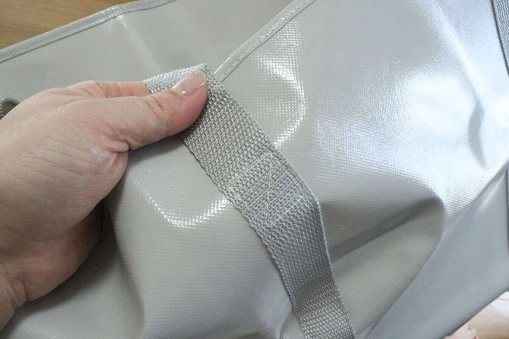 女性の手がジッパー付バッグの持ち手部分を掴み縫製を確認