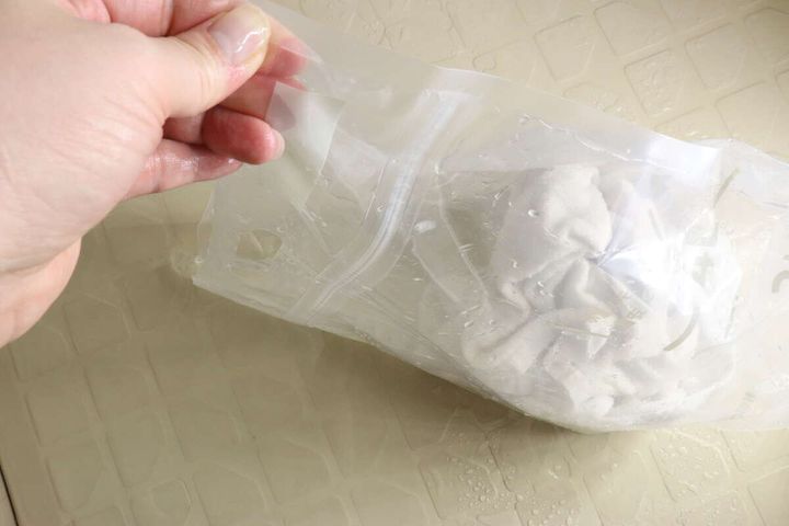水の入った「つけ置き洗いバッグ」の持ち手を片手で持っている