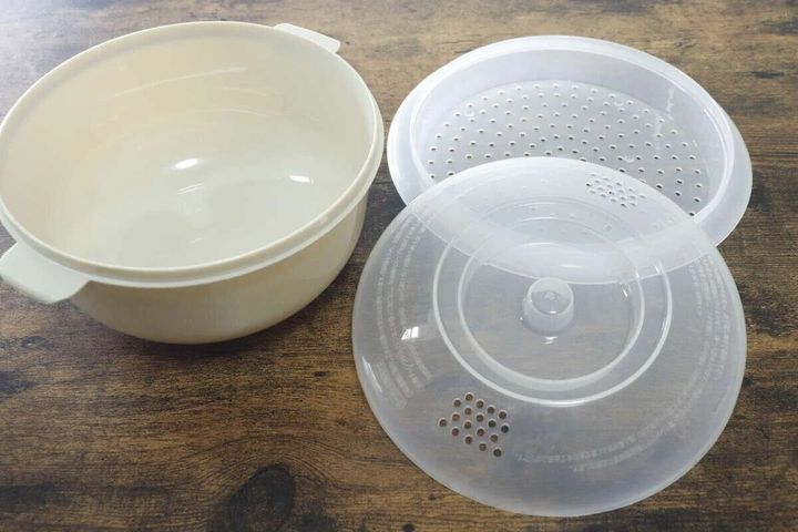 電子レンジ調理器の白い本体とザル、透明なフタが置かれている