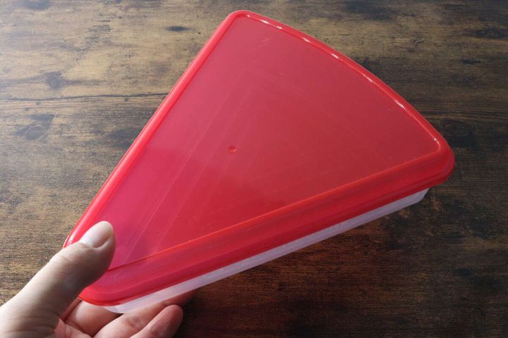 赤いフタの三角形の保存容器を左手で持っている