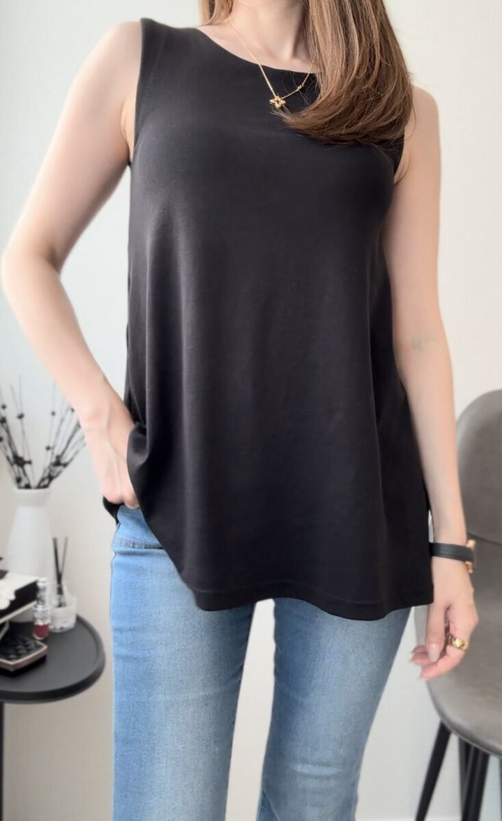 黒いAラインノースリーブとジーンズを着た女性