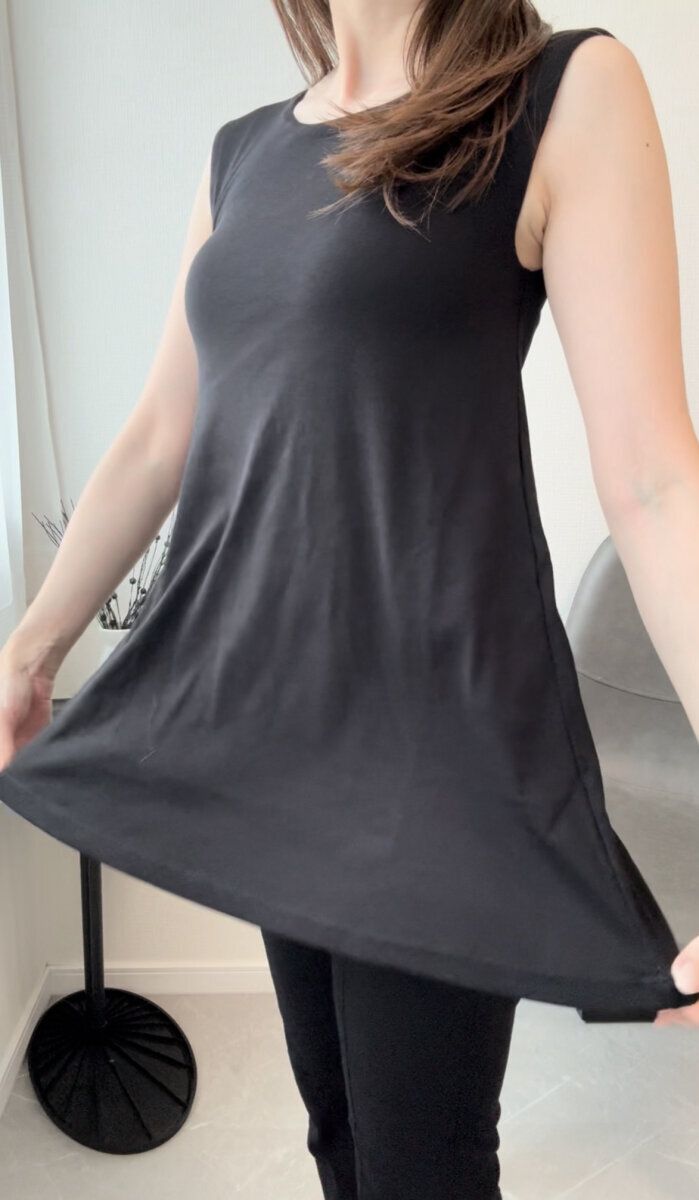 黒いトップスを着た女性が裾を広げAラインを見せる