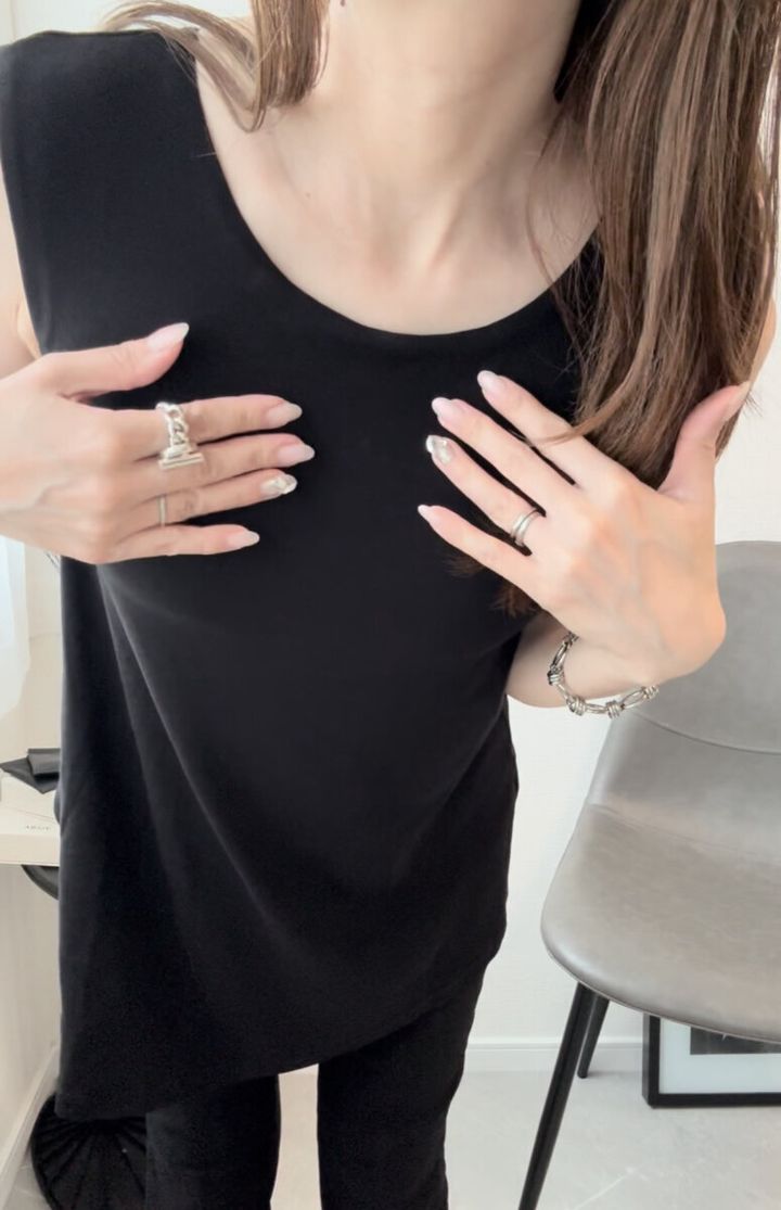黒いトップスを着た女性が胸元に手を当てている