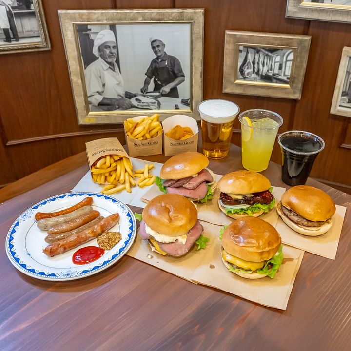 バーガーとソーセージ、ポテト、ドリンクがそろったテーブル