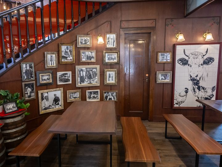 精肉店の白黒写真とタイルアートに囲まれたテーブル席