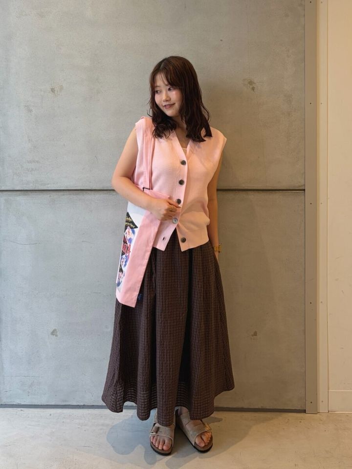ピンクのニットベストとブラウンフレアスカートの女性