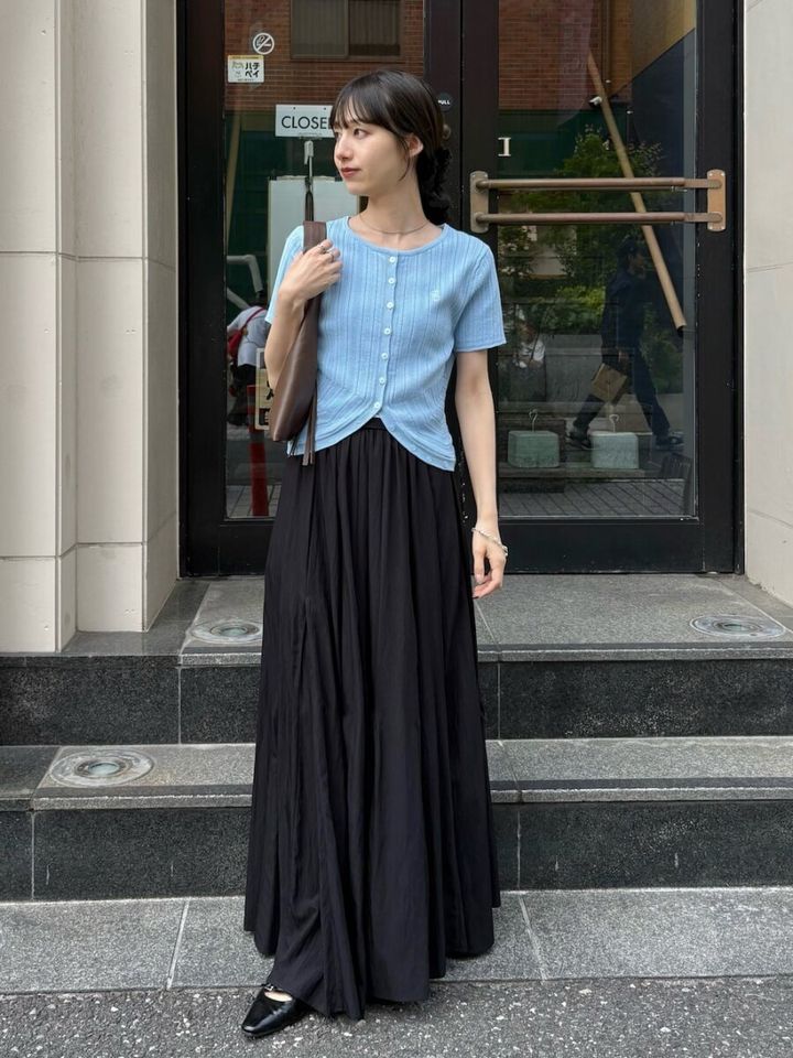 アイスブルーのカーデと黒ロングスカートの女性