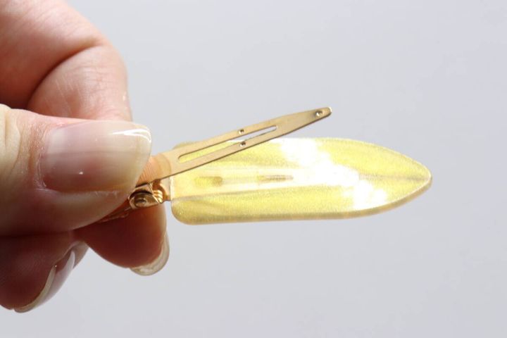女性の指で持たれたヒョウ柄前髪クリップの裏面とゴールドの留め具