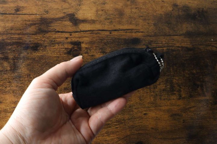 女性の手のひらに黒い長方形のキーホルダーポーチが乗っている。ポーチのサイズ感がわかる