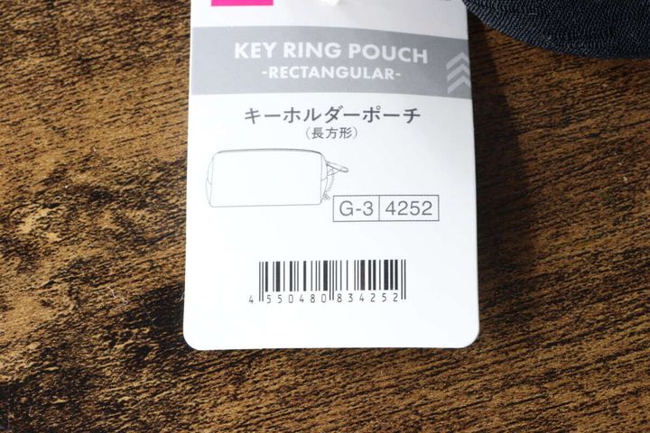 黒いキーホルダーポーチに付いている商品タグのアップ。商品名とJANコードが見える