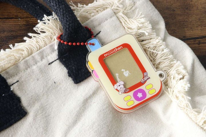 フリンジ付きの白いバッグに、アクリルフォトカードチャームを付けた様子