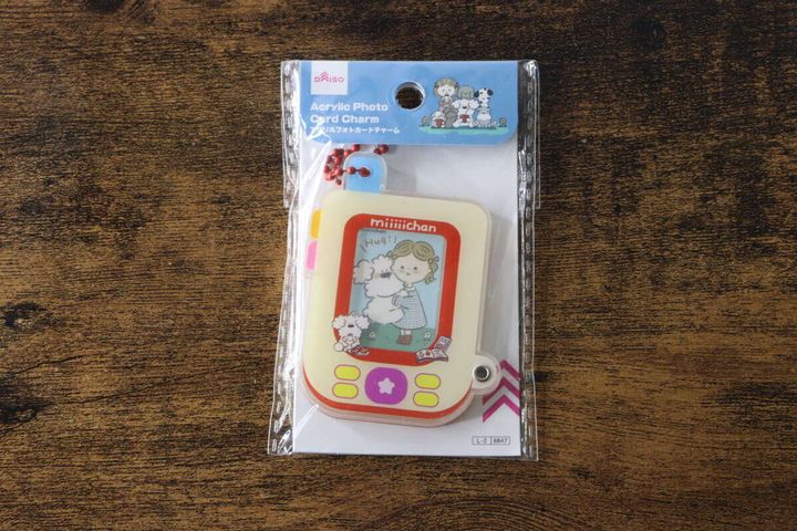 木目のテーブルに置かれた、パッケージ入りのアクリルフォトカードチャーム