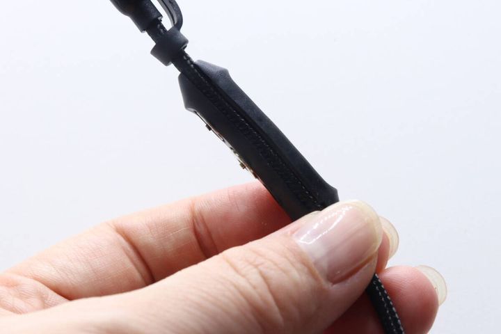 女性の指がマグネット端子ケーブルの中間にある収納部分を持つ