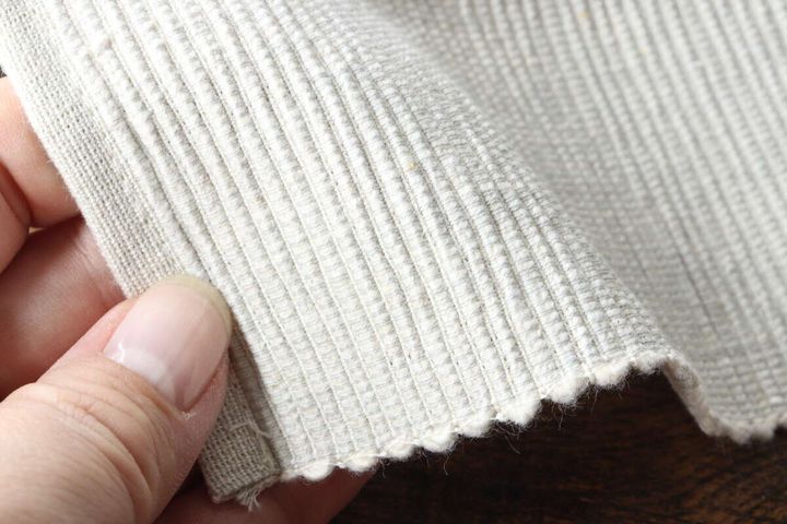 指でセルビッジランチョンマットの厚みと織り目をアップで示している