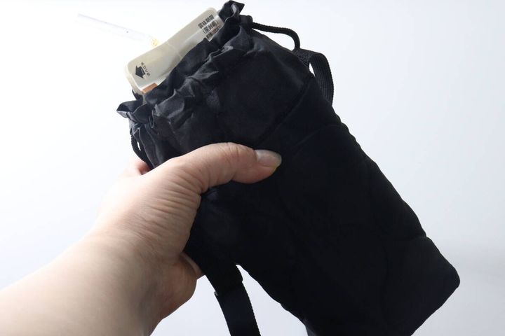 手が900mlの牛乳パック型飲料が入ったボトルホルダーを持っている