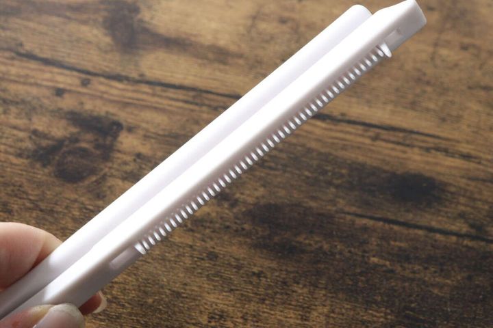 白いブロー用ストレートコームの挟む部分を指で開いている様子