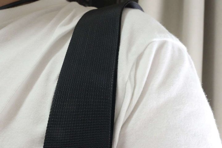 白いTシャツを着た肩に黒いストラップをかけている